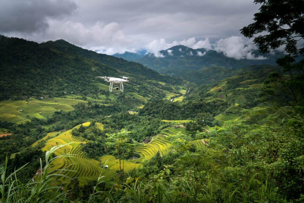 Aerial view of a drone flying above verdant rice terraces in mountainous countryside.